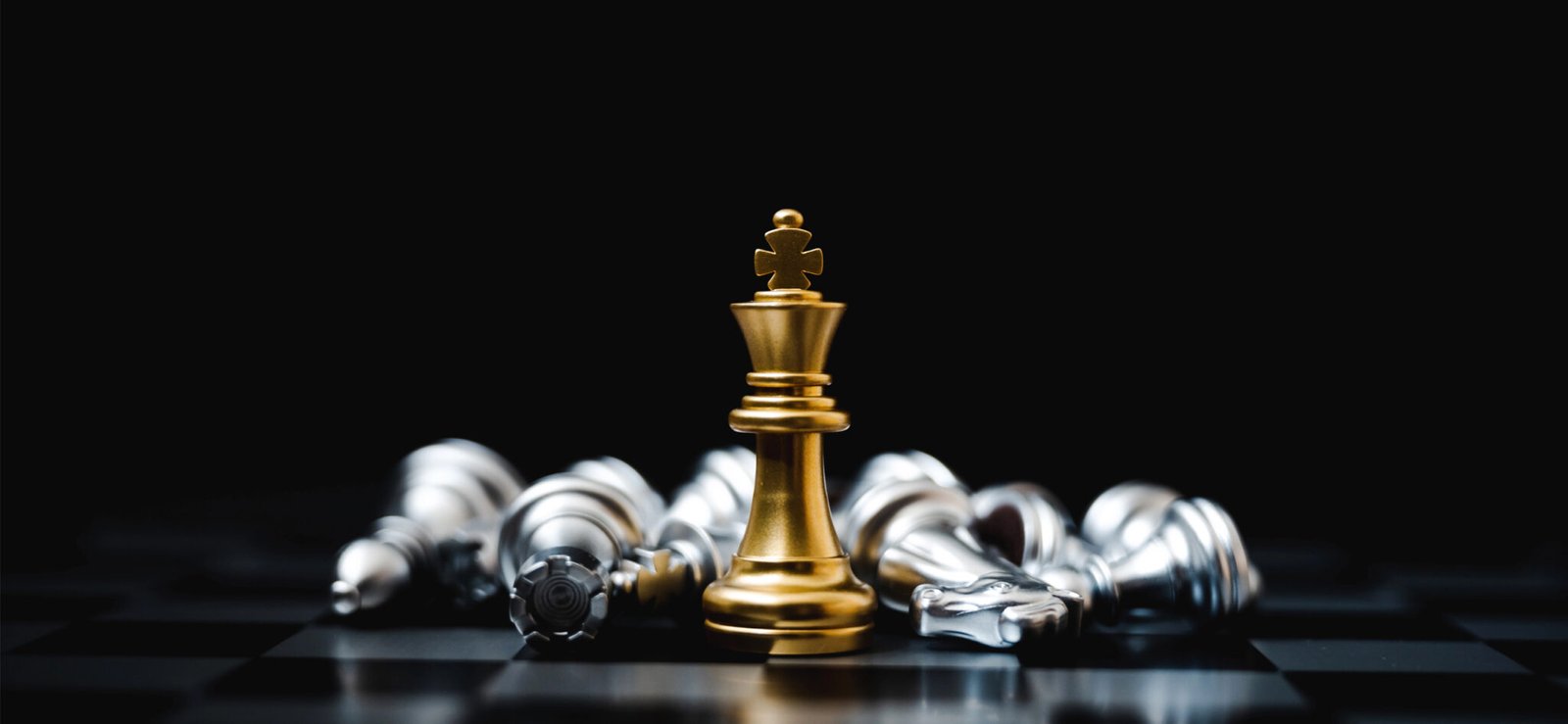 Re degli scacchi dorato unico sopravvissuto circondato da tutti i pezzi avversari sconfitti.